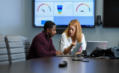 student and mentor talking while reviewing a laptop with graphs in the background